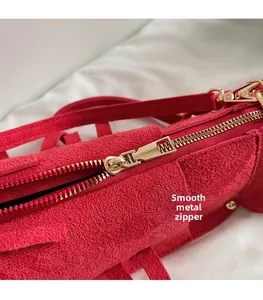 Detail of high-quality gold zipper on red suede lobster-shaped shoulder bag