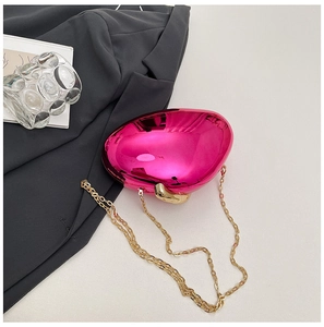 Chic rose pink mirrored acrylic clutch bag with gold chain on dark grey suit fabric