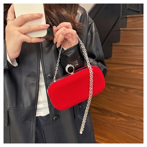 Detail of red velvet evening bag featuring rhinestone ring clasp and silver chain strap