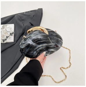 Detailed macro view of marble pattern acrylic clutch with moon-shaped gold metal clasp