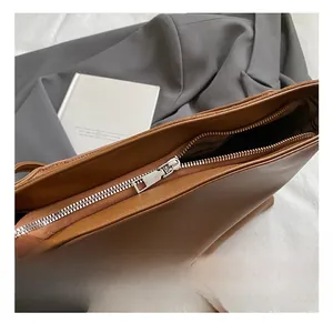 Détail d'une fermeture éclair argentée et cuir marron sur un sac seau élégant