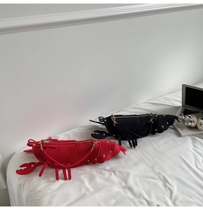 Detailed view of red and black lobster shaped crossbody bags with gold rivet accents