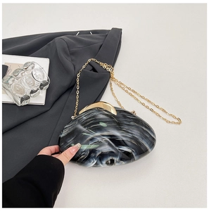Macro shot of marble textured acrylic clutch bag with elegant golden metal clasp