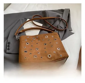 Détails du sac bandoulière en daim fauve avec œillets métalliques et fine sangle en cuir