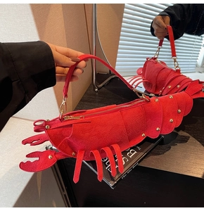 Macro detail of red lobster-shaped bag featuring matte texture and gold rivet studs