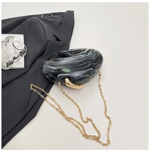 Detail of marble pattern acrylic evening bag with gold handle and metal chain strap