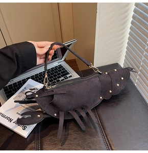 Close-up of black lobster shaped crossbody bag with gold rivet accents and matte finish