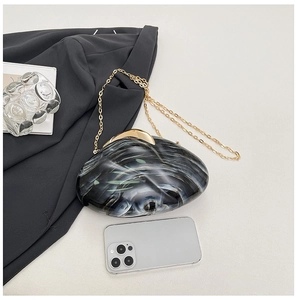 Detailed macro shot of the black and white marble acrylic clutch with gold metal chain