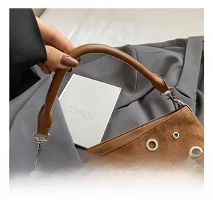 Détail montrant la texture mate marron et les rivets métalliques de ce sac à bandoulière