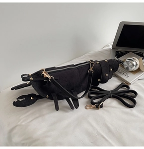 Close-up of matte lobster-shaped crossbody bag with gold studs and a zipper detail