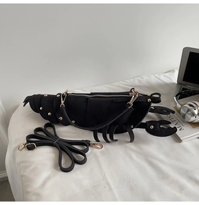 Detail of creative black suede lobster bag with gold rivets and metallic zipper
