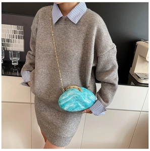 Blue marble acrylic evening bag with gold chain strap shown on a model outfit