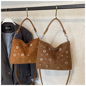 Détail de sacs Hobo en daim avec œillets métalliques en tons caramel et marron foncé