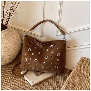 Gros plan d'un sac seau en daim marron avec œillets métalliques et bandoulière réglable