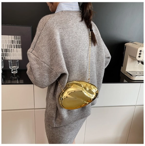 Close-up of golden mirror acrylic evening bag with artistic irregular shape and chain
