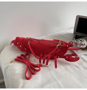 Detail of red lobster crossbody bag with matte texture, gold rivets, and top zipper closure