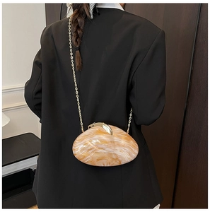 Detail view of marble pattern acrylic evening clutch with gold chain on black blazer