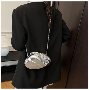 Silver mirror-effect acrylic clutch bag with organic lava shape on a model's black blazer