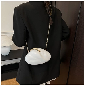 Detail of white marble acrylic clutch bag with gold shell clasp and elegant chain strap