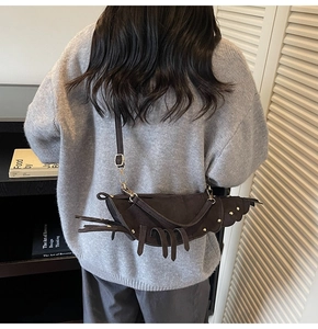 Detail shot of creative lobster-shaped crossbody bag in dark brown matte leather on model