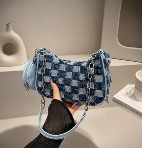 Detail of blue denim checkerboard bag featuring frayed edges and silver chain strap