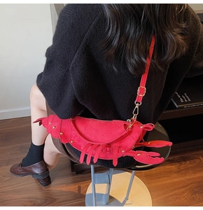 Detailed close-up of a creative red lobster shaped crossbody bag with metallic gold buckles