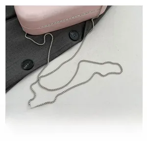 Detail of pink acrylic evening bag with fine silver chain strap on grey fabric