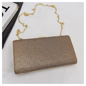 Close-up of champagne gold rhinestone evening clutch bag with glossy metal chain strap