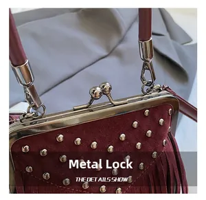 Detail of silver hardware clasp and rivets on burgundy suede handbag with tassels