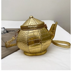 Detail of creative gold teapot-shaped bag featuring embossed crocodile texture and zipper