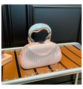 Detail of pink acrylic evening bag featuring silver metal handle and rhinestone tassels