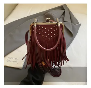 Detail of vintage burgundy handbag with metal rivets, fringe tassels and retro metal clasp