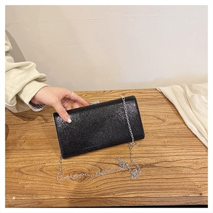 Close-up of elegant black rhinestone clutch bag with silver chain strap and metal frame