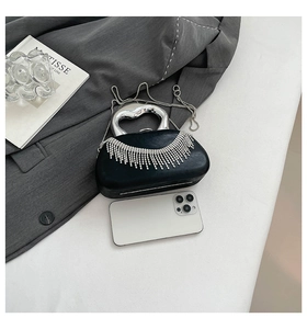 Detail of black acrylic evening bag with silver rhinestone fringe and metal handle