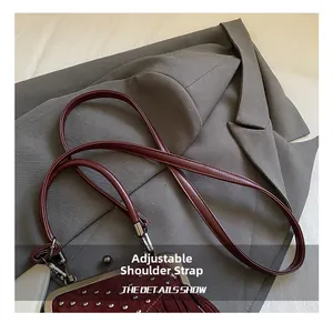 Detail view of burgundy leather fringe bag with rivets and adjustable shoulder strap