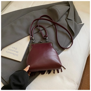 Detail of vintage burgundy kiss-lock bag with leather tassels and round top handles