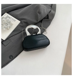 Detail of black leather clutch featuring a sculptural silver liquid metal handle and chain