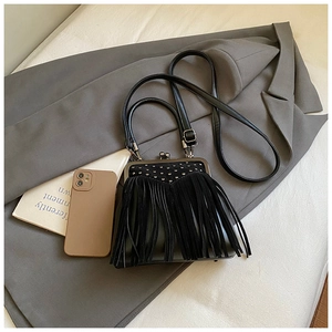 Top view of black fringe crossbody bag with metal studs on a grey blazer backdrop