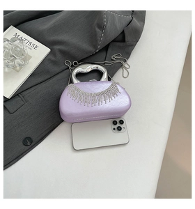 Detail of purple evening bag with rhinestone fringe next to smartphone for size scale