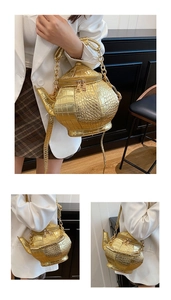 Detailed view of the 3D gold teapot-shaped handbag with crocodile pattern texture