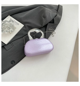 Detail of lavender textured bag with silver curved handle and metal chain on a blazer