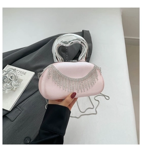 Detail of light pink satin evening bag with silver rhinestone tassels and metal handle