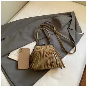 Detailed view of olive green fringe handbag with rivets and vintage clasp on grey blazer