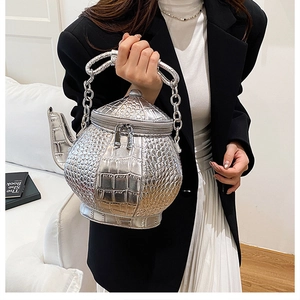 Detail of silver crocodile pattern teapot shaped bag with metallic chain and zipper