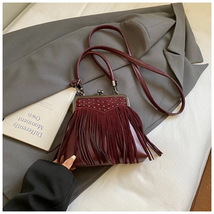 Detail of vintage wine red leather crossbody bag with fringe tassels and metal studs