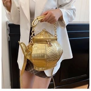 Detail of creative gold teapot bag with crocodile texture and metallic chain handle