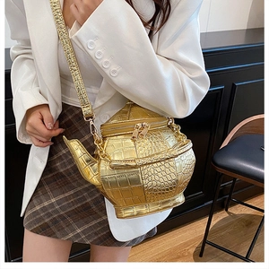 Detailed macro view of the gold teapot shaped bag with crocodile pattern and dual zippers