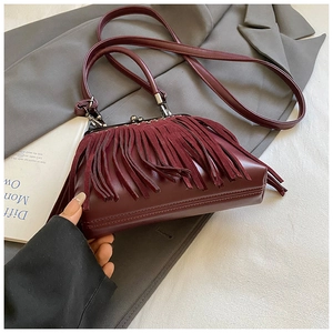 Detail of burgundy fringe crossbody bag on grey suit with vintage clasp closure