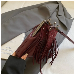 Close-up of wine red fringe crossbody bag with silver rivets and vintage metal clasp