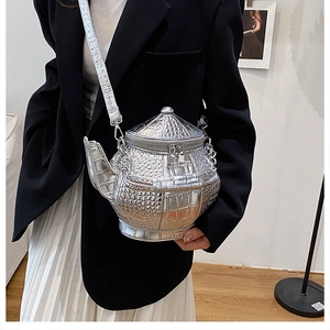 Macro view of silver teapot shaped crossbody bag with metallic crocodile embossing